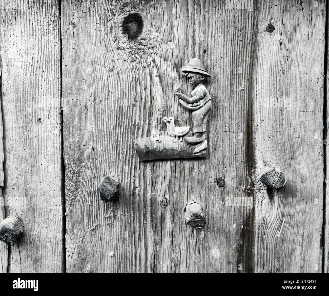 Ein kleiner Junge, in Holzgänse geschnitzt, Plastikfigur auf einer Planktür im Ulten-Tal, Südtirol Stockfoto