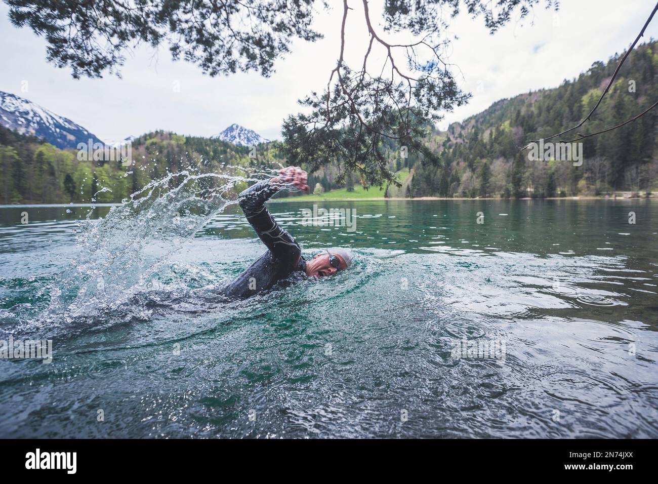 Professioneller Triathlet Schwimmen, Training in einem klaren Bergsee in Allgäu, Alatsee, Bayern, Deutschland Stockfoto