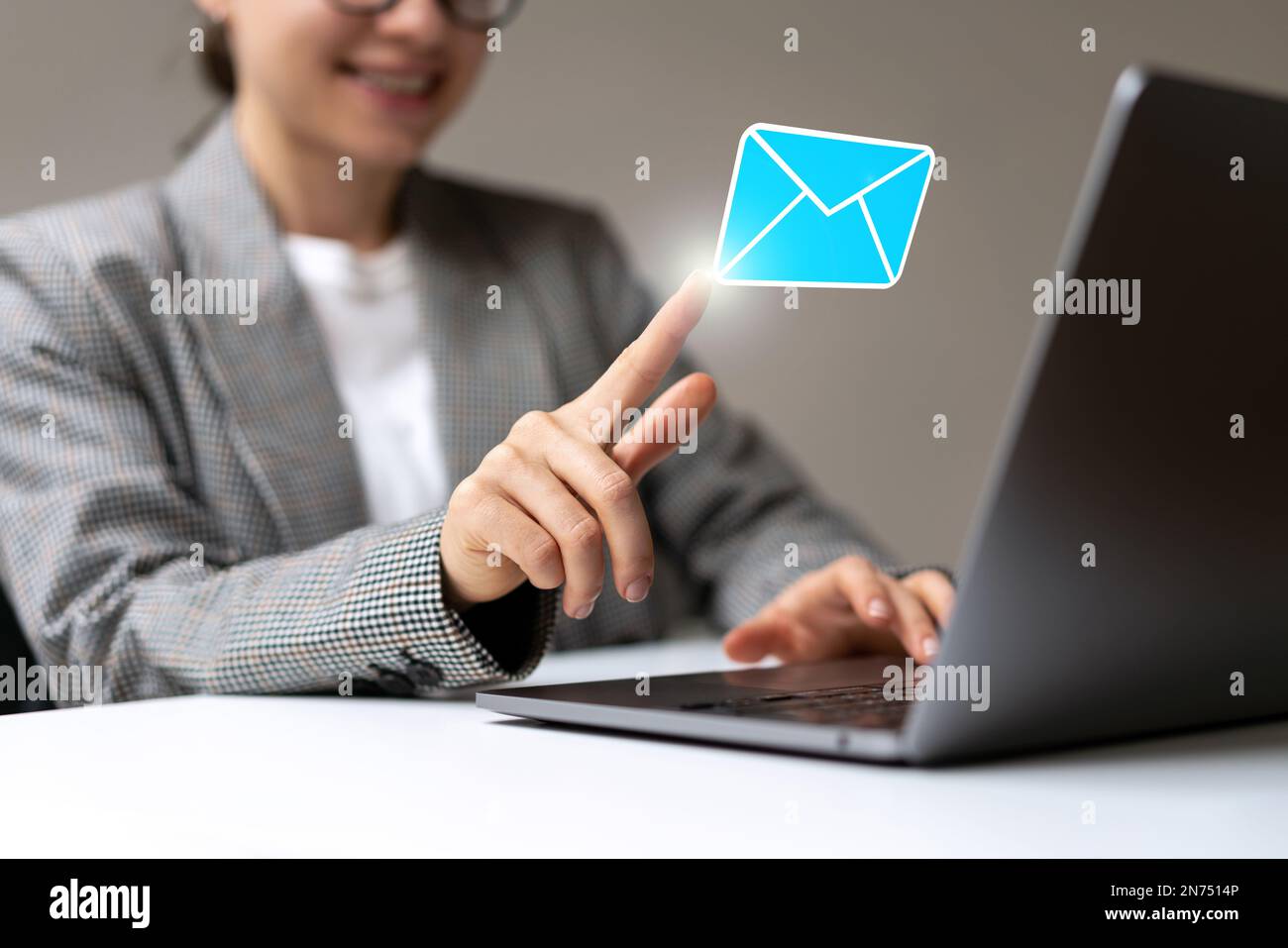 Junge Geschäftsfrau, die virtuelle E-Mails öffnet, indem sie mit dem Finger auf den Umschlag für digitale Post drückt. Stockfoto
