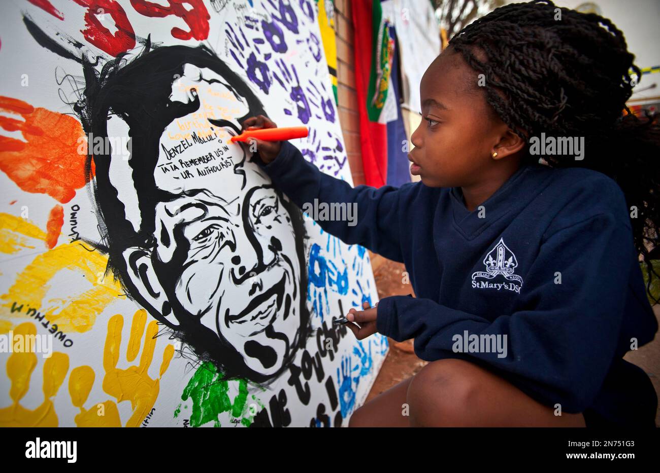 Ayanda Mkhize, 7, writes a get-well message on a painting of Nelson Mandela made by another class at the St Mary's Diocesan School for Girls and left outside the Mediclinic Heart Hospital where former South African President Nelson Mandela is being treated in Pretoria, South Africa, Wednesday, July 17, 2013. Nelson Mandela has made "dramatic progress," and may be going home "anytime soon," his daughter Zindzi said Wednesday on the eve of his 95th birthday, a day declared by the United Nations as a way to recognize the Nobel Prize winner's contribution to reconciliation. (AP Photo/Ben Curtis) Stockfoto