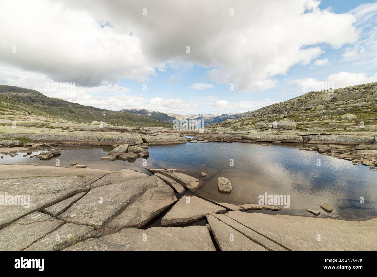 Aussicht während der Wanderung nach Trolltunga, Norwegen an einem Sommertag - Reflexion von Wolken in einem Teich aus Wasser. Stockfoto