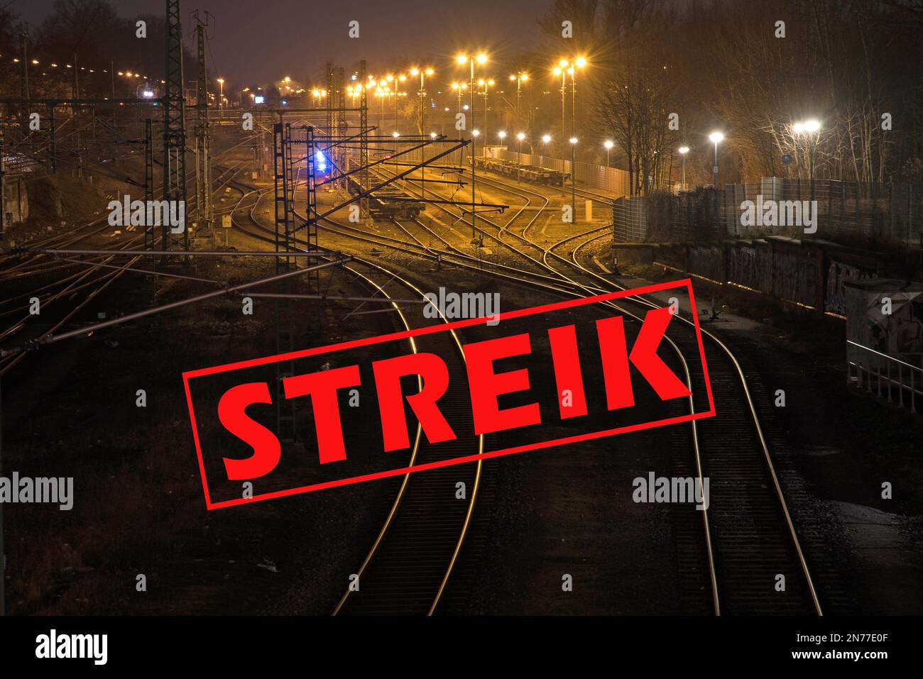 Deutscher Text Streik (was Streik bedeutet) über glänzende und kurvige Bahngleise in der Nacht in einem Frachtraum, Kopierraum, ausgewählter Fokus Stockfoto