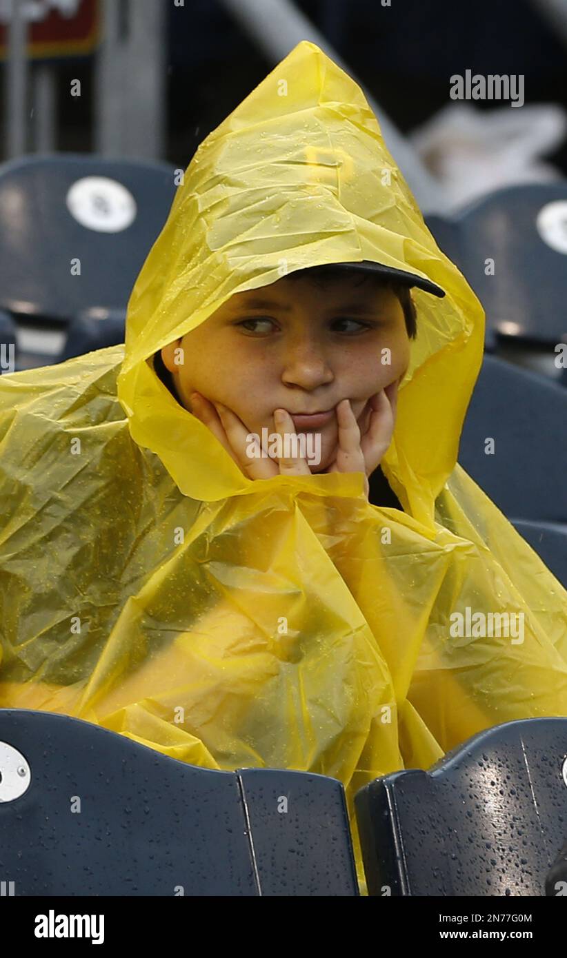 A young baseball fan wears a yellow poncho as he waits out a rain delay in the baseball game between the Pittsburgh Pirates and the Milwaukee Brewers on Sunday, June 30, 2013, in Pittsburgh. (AP Photo/Keith Srakocic) Stockfoto