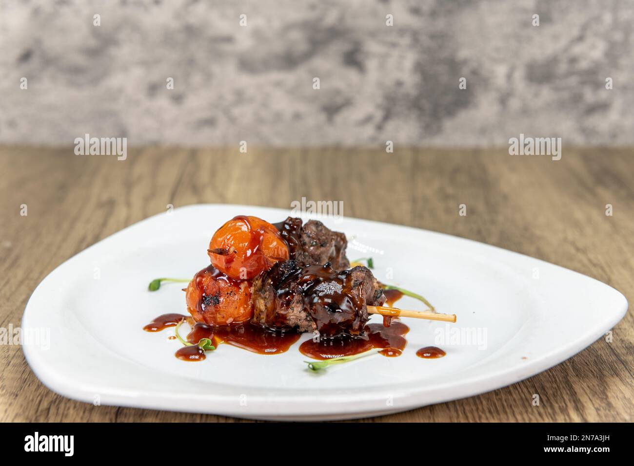 Verführerische Vorspeise aus glasiertem Rinderspieß, serviert auf einem kleinen Teller. Stockfoto