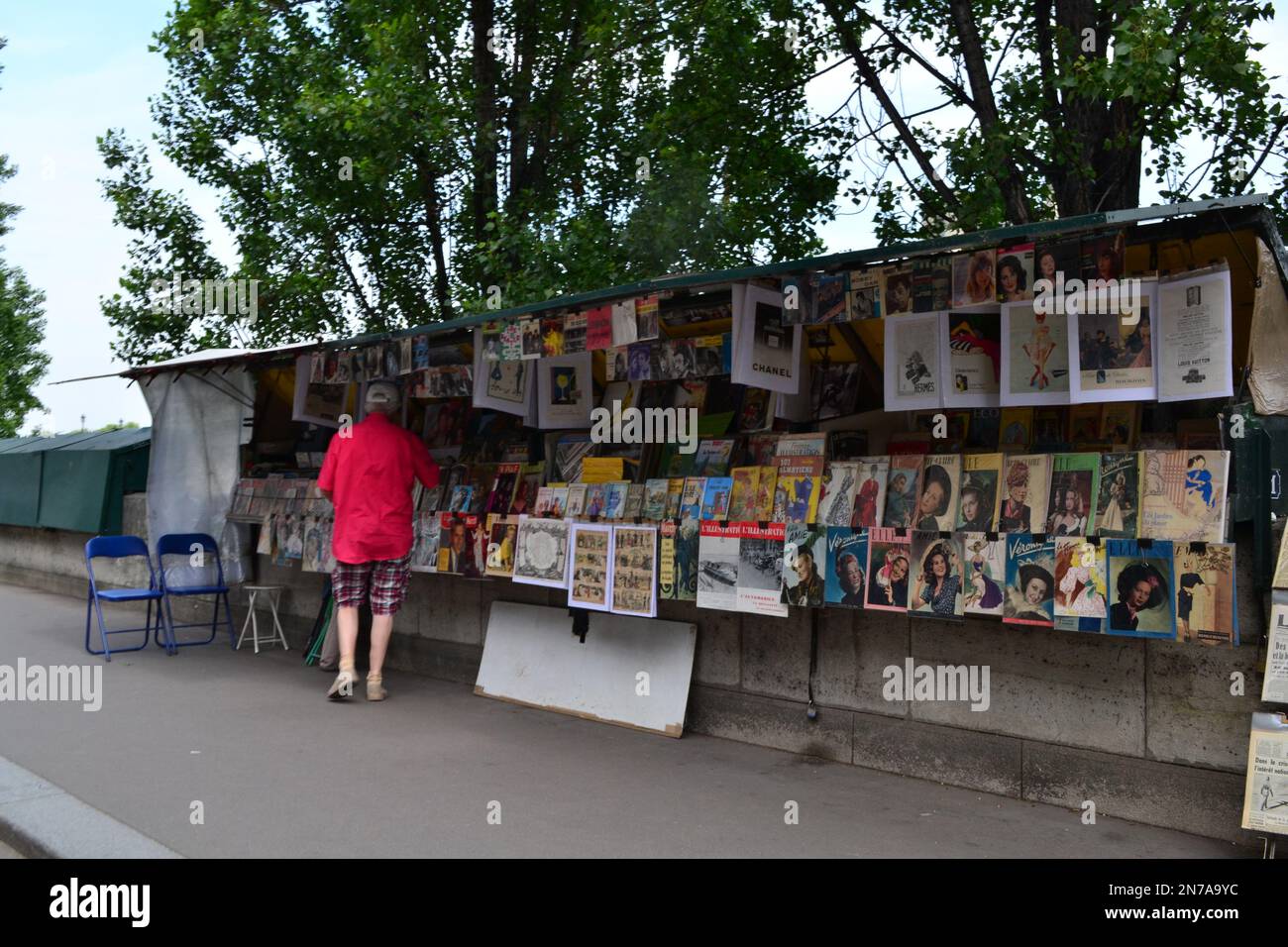 Ein Mann, der sich auf dem Bürgersteig Nachrichten und einen Zeitschriftenstand in Paris ansieht. Stockfoto