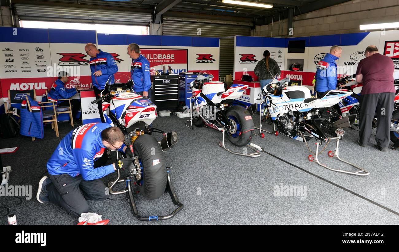 Rennmotorräder, die von Mechanikern unter einem Sonnendach in einem Rennpaddock gewartet und vorbereitet werden. Stockfoto