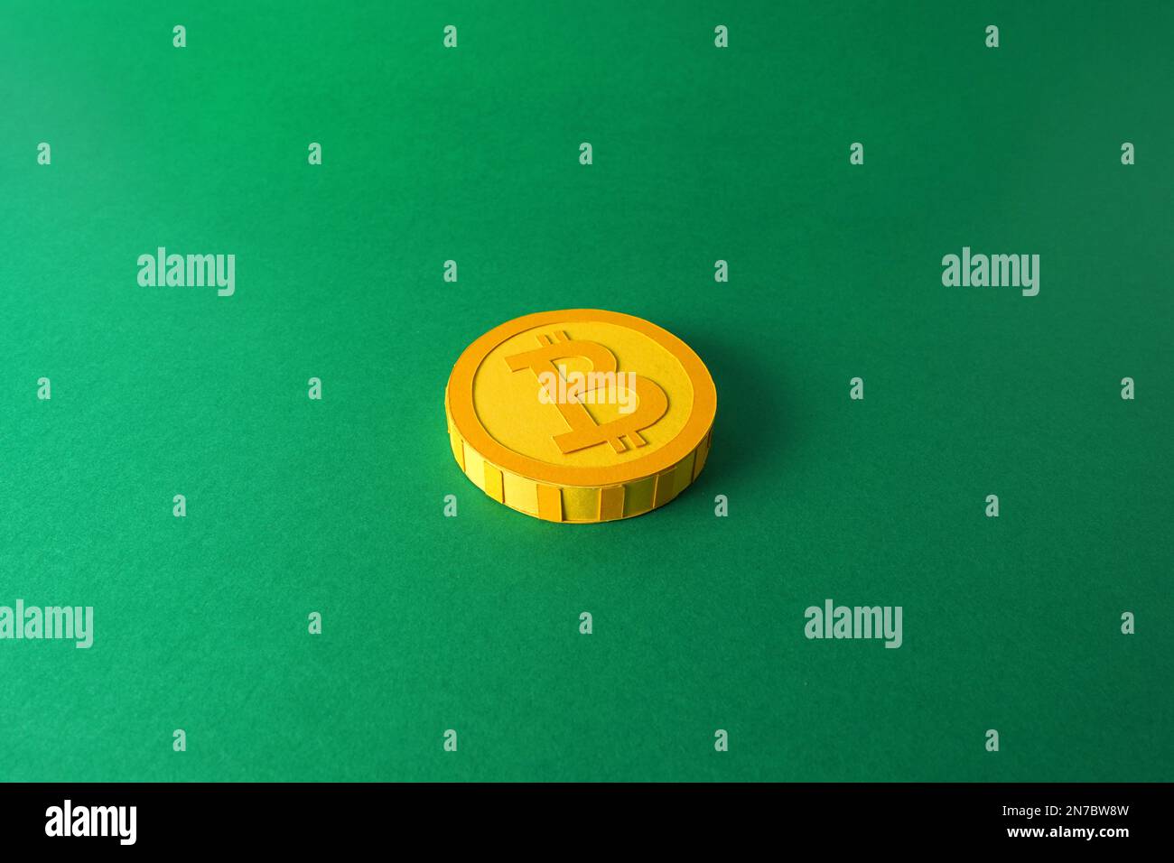 Papierausschnittsmodell eines gelben 3D-Bitcoin-Tokens auf minimalistischem Hintergrund, Krypto-Blockchain papercraft-Kunst auf flachem grünen Hintergrund Stockfoto