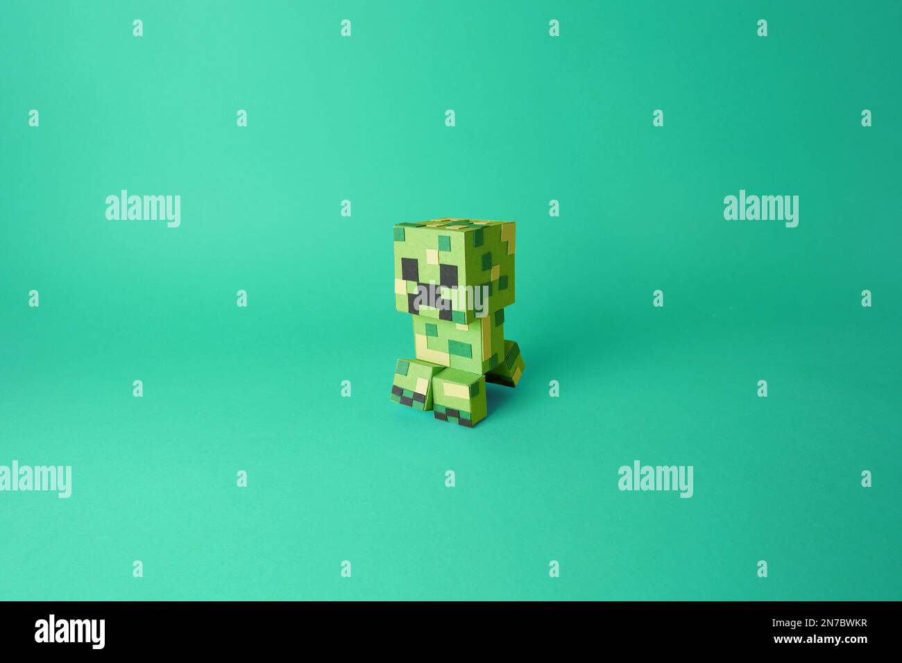 Papercraft einer isolierten Videospielfigur aus Minecraft, Creeper. Farbiges, grünes Papier, ausgeschnittene Modellkunst Stockfoto