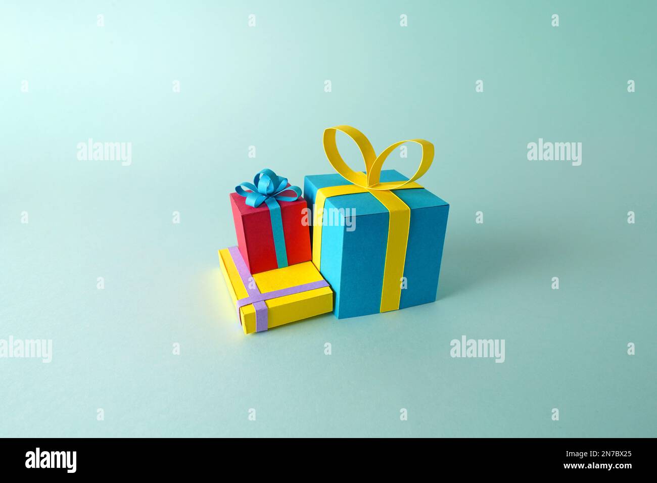 Eine Gruppe von Geschenkmodellen und Geschenken zu Weihnachten, Geburtstagen oder zum Valentinstag aus farbigem Papier auf flachem Hintergrund Stockfoto