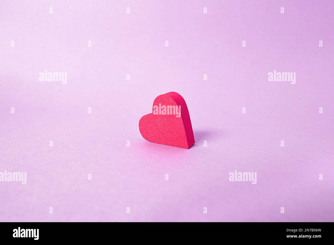 Mit Papier ausgeschnittene rote Herzen auf einem schönen lavendelfarbenen Hintergrund, gefertigt von Leidenschaft und Liebe für St. Valentinstag, Hochzeiten, Jubiläum oder Muttertag Stockfoto