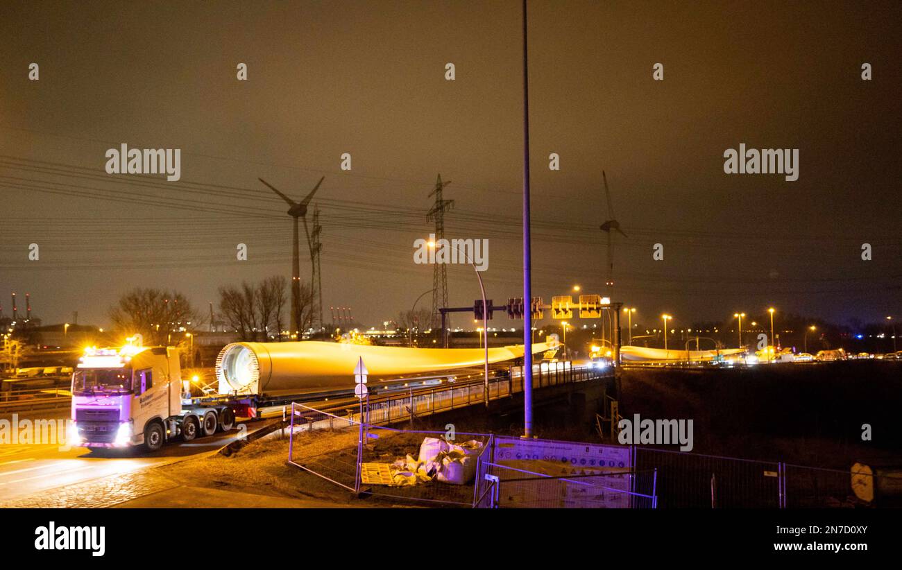 Hamburg, Deutschland. 10. Februar 2023. Ein Schwerlasttransport mit Rotorblättern für eine neue Windturbine ist auf dem Weg von der Autobahnausfahrt Waltershof im Hamburger Hafen zur Kläranlage Dradenau. Drei schwere Lkw brachten am Samstagabend große Teile einer neuen Windturbine nach Hamburg-Waltershof. Nach Angaben des Betreibers der Kläranlage Hamburg Wasser wird die neue Windturbine eine Leistung von 3,6 Megawatt haben und jährlich 9.000 Megawatt-Stunden Strom liefern. Kredit: Christian Charisius/dpa/Alamy Live News Stockfoto