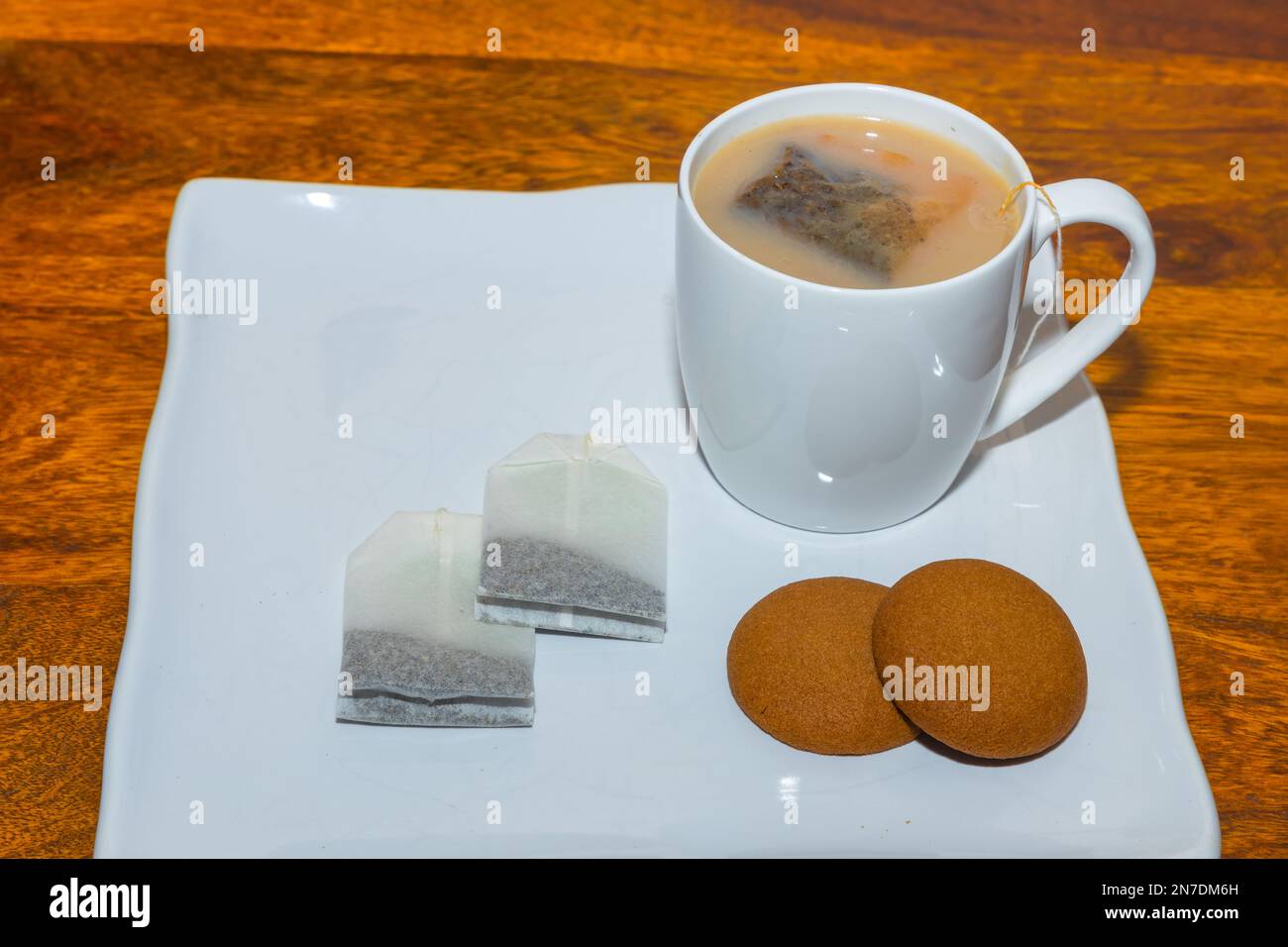 Eine weiße Tasse mit Tee oder Kaffee zusammen mit Keksen auf einem Holztisch mit Kopierbereich Stockfoto