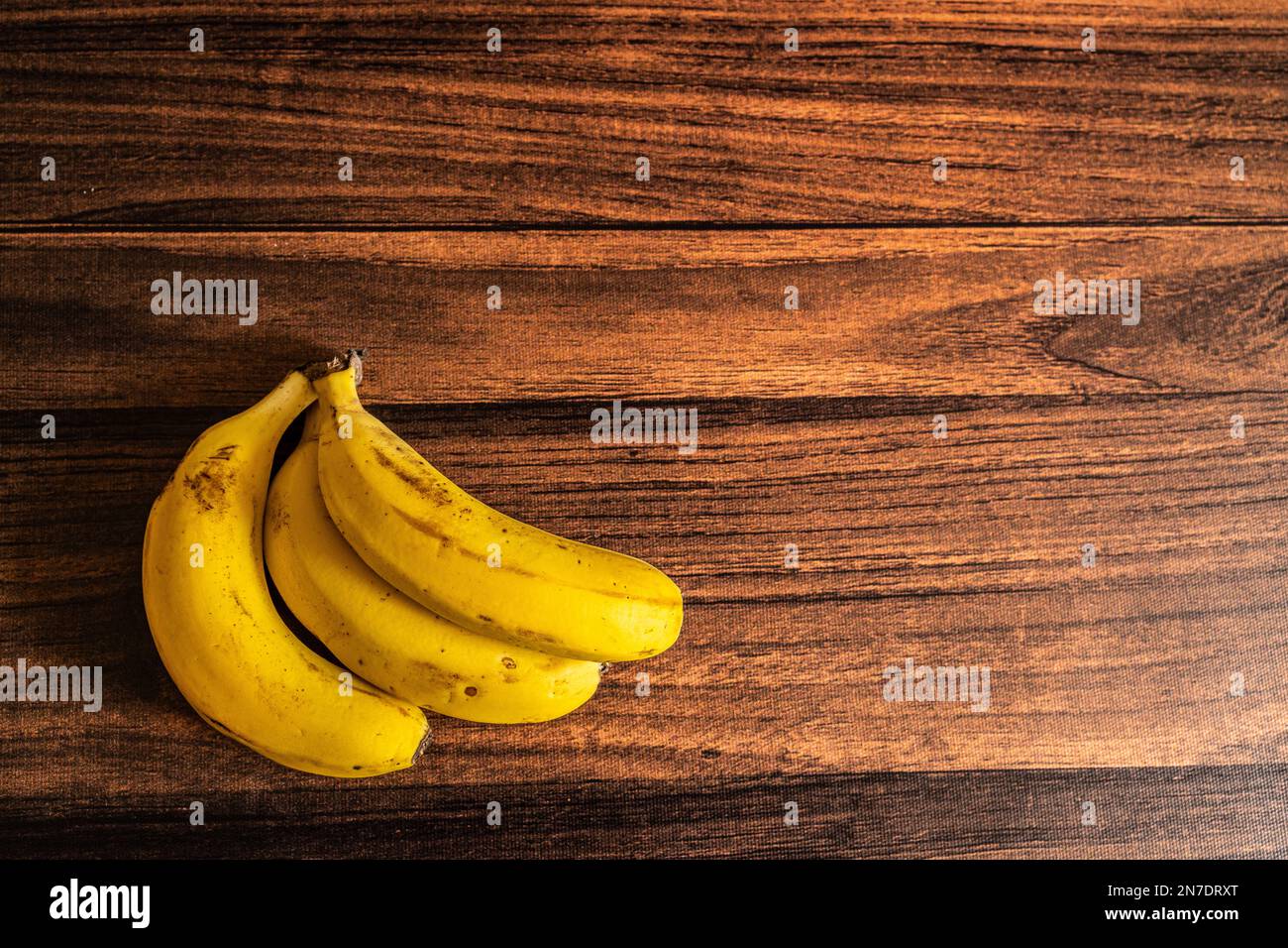 Ein Haufen reifer Bananen auf einem Holztisch mit Platz für Kopien Stockfoto