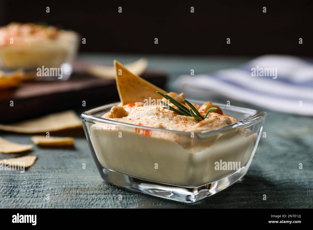 Köstlicher hausgemachter Hummus in Glasschüssel auf Holztisch Stockfoto