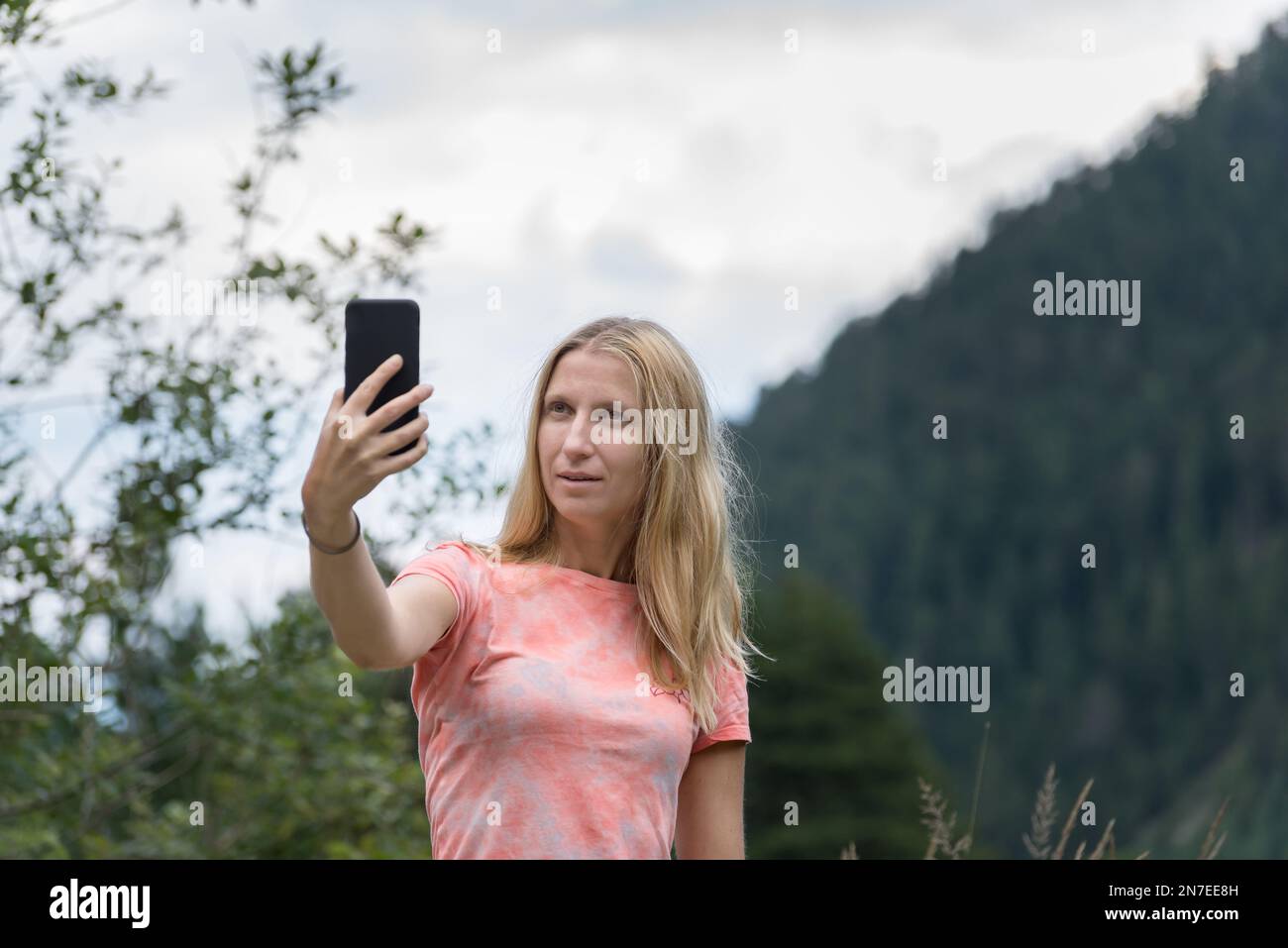 Wunderschöne, blonde, weiße Frau, die draußen im Park ein Selfie mit dem Smartphone macht Stockfoto