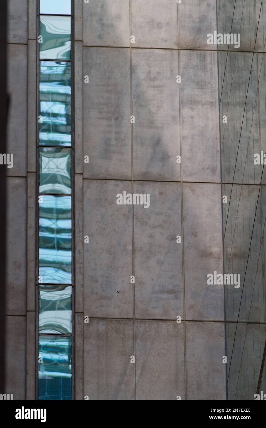 Abstrakter Gebäudehintergrund mit Betonwandstruktur und reflektierenden Glaspaneelen in Melbourne, Australien. Stockfoto