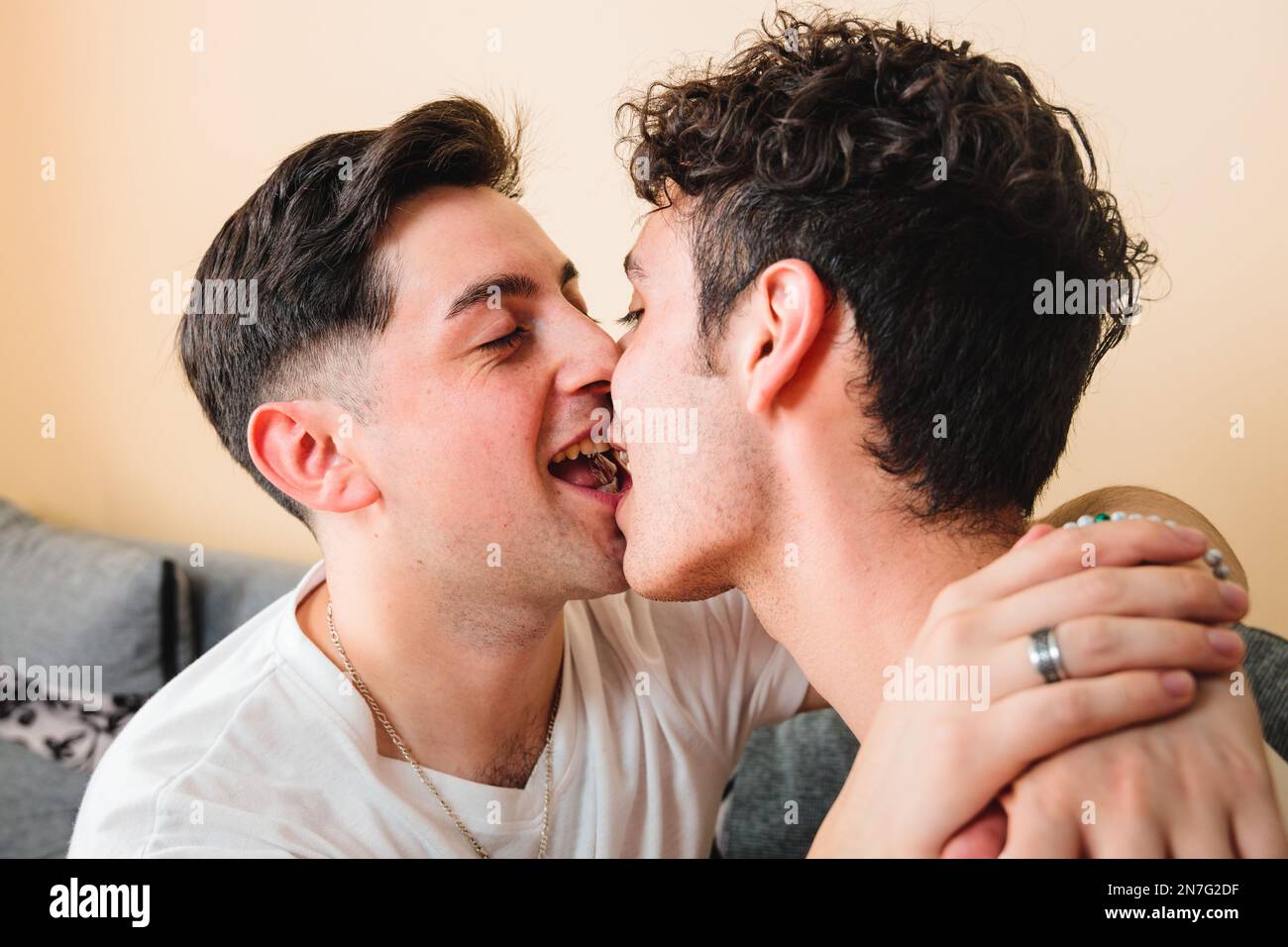 Nahaufnahme eines schwulen Paares, das sich romantisch auf den Mund küsst, spielt und lächelt. LGBT-Beziehung Stockfoto