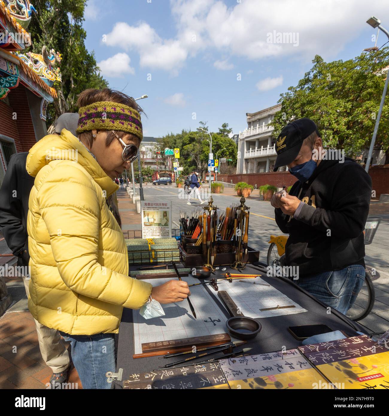 Eine Frau probiert einen Kalligrafiepinsel an einem Straßenstand in Taipei, Taiwan. Stockfoto