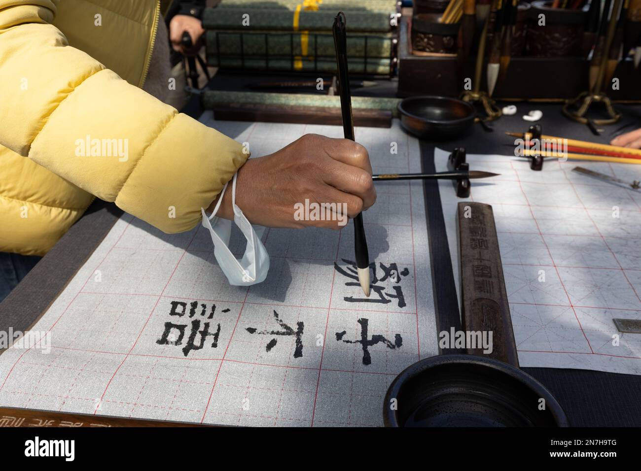 Eine Frau probiert einen Kalligrafiepinsel an einem Straßenstand in Taipei, Taiwan. Stockfoto
