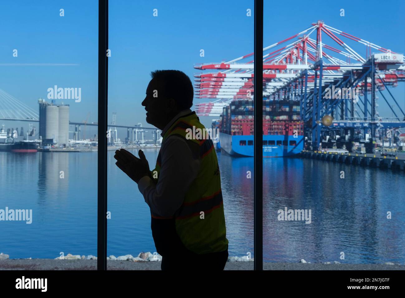 Das COSCO Shipping Andes-Schiff im Hintergrund als Anthony Otto wird als Silhouette dargestellt. CEO von Long Beach Container Terminal erläutert seinen Plan für die Emissionsfreiheit bis 2030 auf einer Tour durch das Long Beach Container Terminal (LBCT). Die Investition in Höhe von $2,5 Mrd. LBCT, die es einem der weltweit führenden Betreiber von Hafenterminals ermöglicht hat, die Emissionen erheblich zu senken und einen „Netto-Nullpunkt“ in greifbarer Nähe zu haben. Auf dieser Tour erfahren Sie außerdem zum ersten Mal mehr über ein Projekt im Wert von $30 Millionen US-Dollar bei LBCT, bei dem emissionsfreie Frachtumschlagsgeräte eingesetzt werden sollen, und erhalten einen exklusiven Einblick in die Pläne von LBCT zur vollständigen Dekarbonisierung der Oper Stockfoto