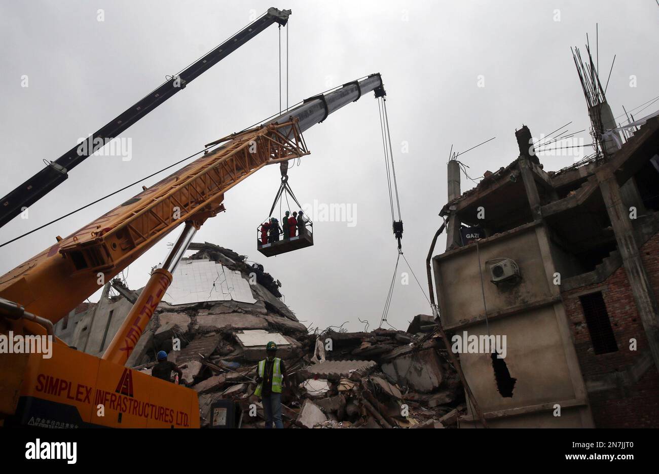 Workers are silhouetted as a crane is used to hoist them up to the