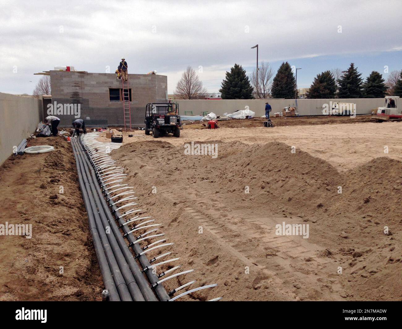 Workers install a heating coil system beneath the practice fields at