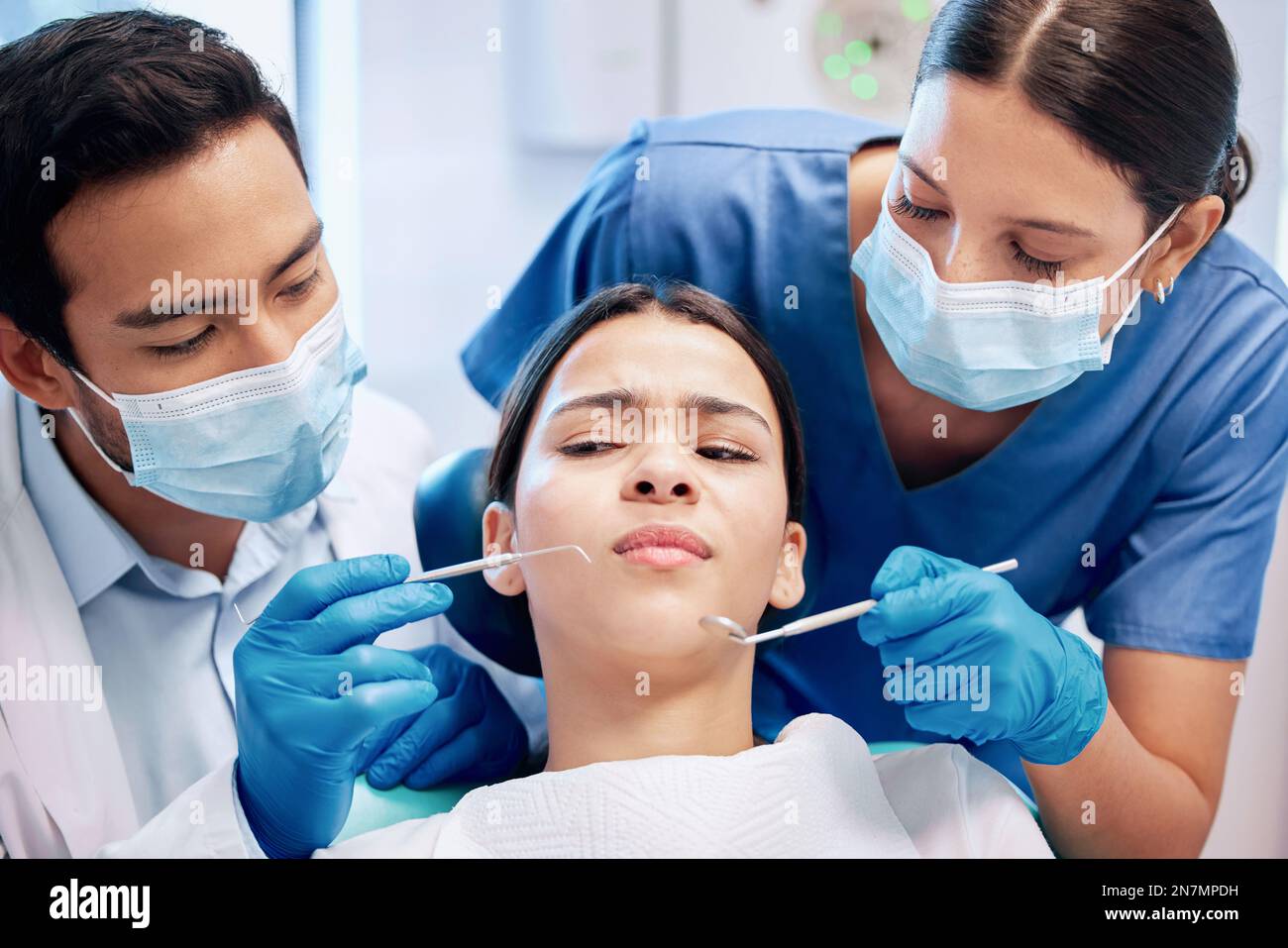 Zu viele Dinge in der Nähe ihres Mundes. Eine junge Frau, die in ihrer Zahnarztpraxis unsicher aussieht. Stockfoto