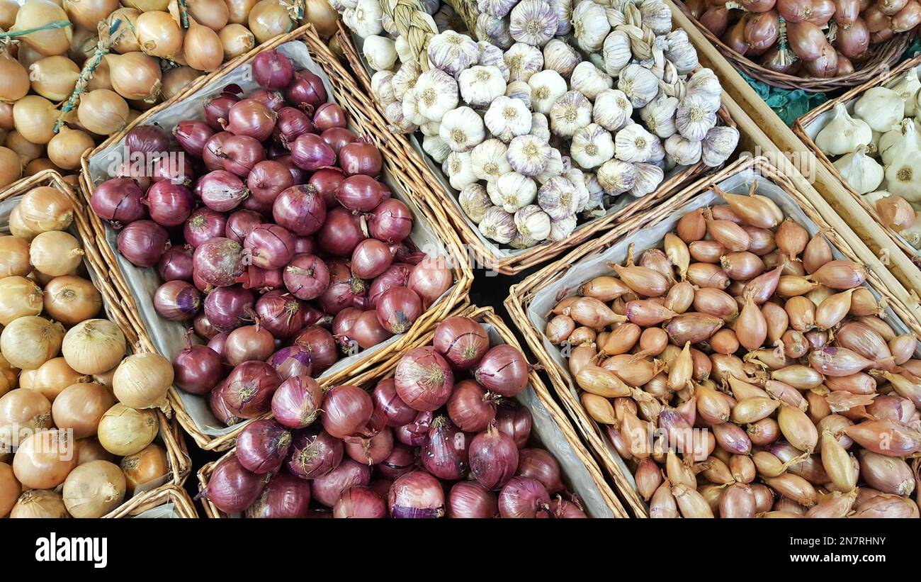 Mischung von Zwiebeln in Verkaufskörben an der Theke Stockfoto