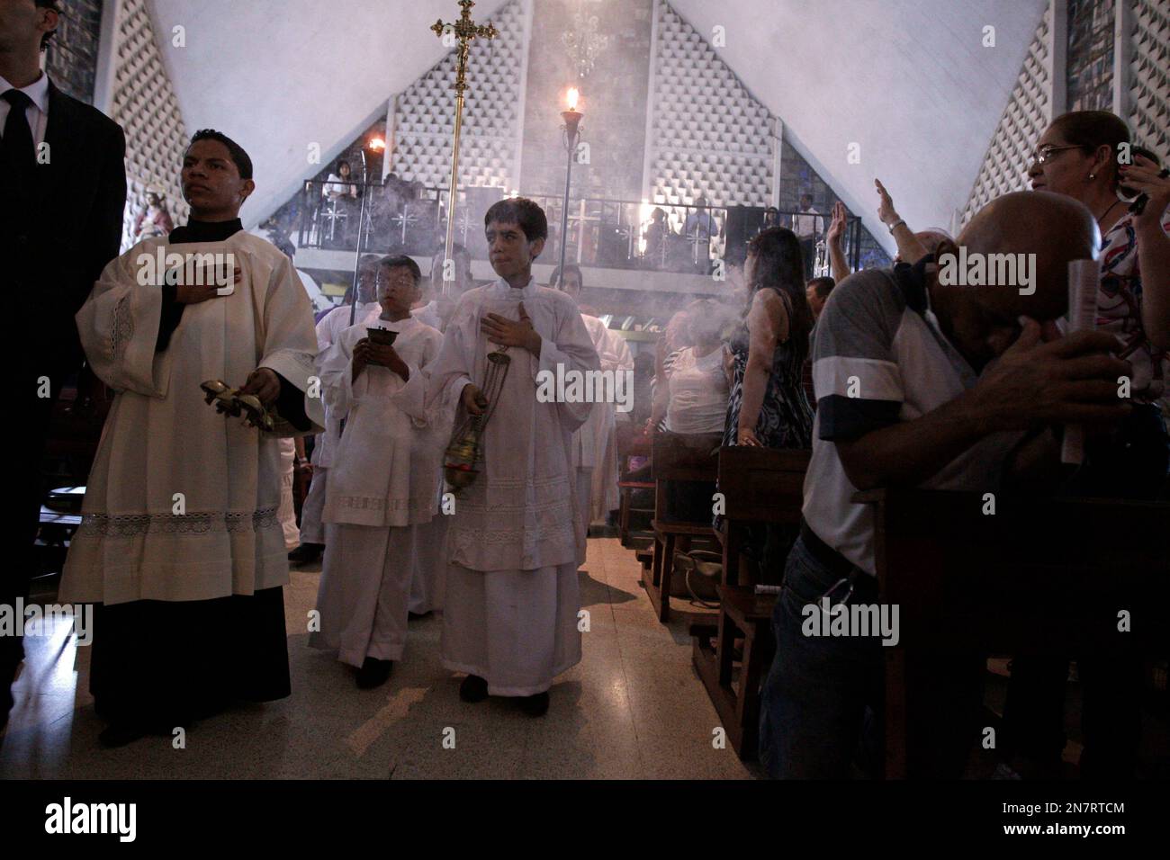 Altar boys burn incense during a Holy Week mass at the Church of Divine