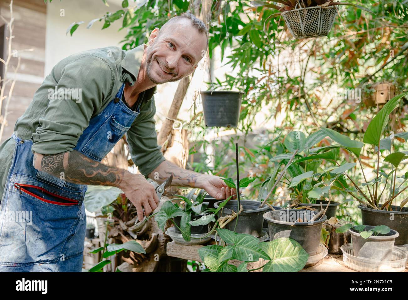 Porträt glücklicher Hipster männlich im Garten Genießen Sie Entspannung zu Hause im Garten Pflanzen Bäume schneiden Stockfoto