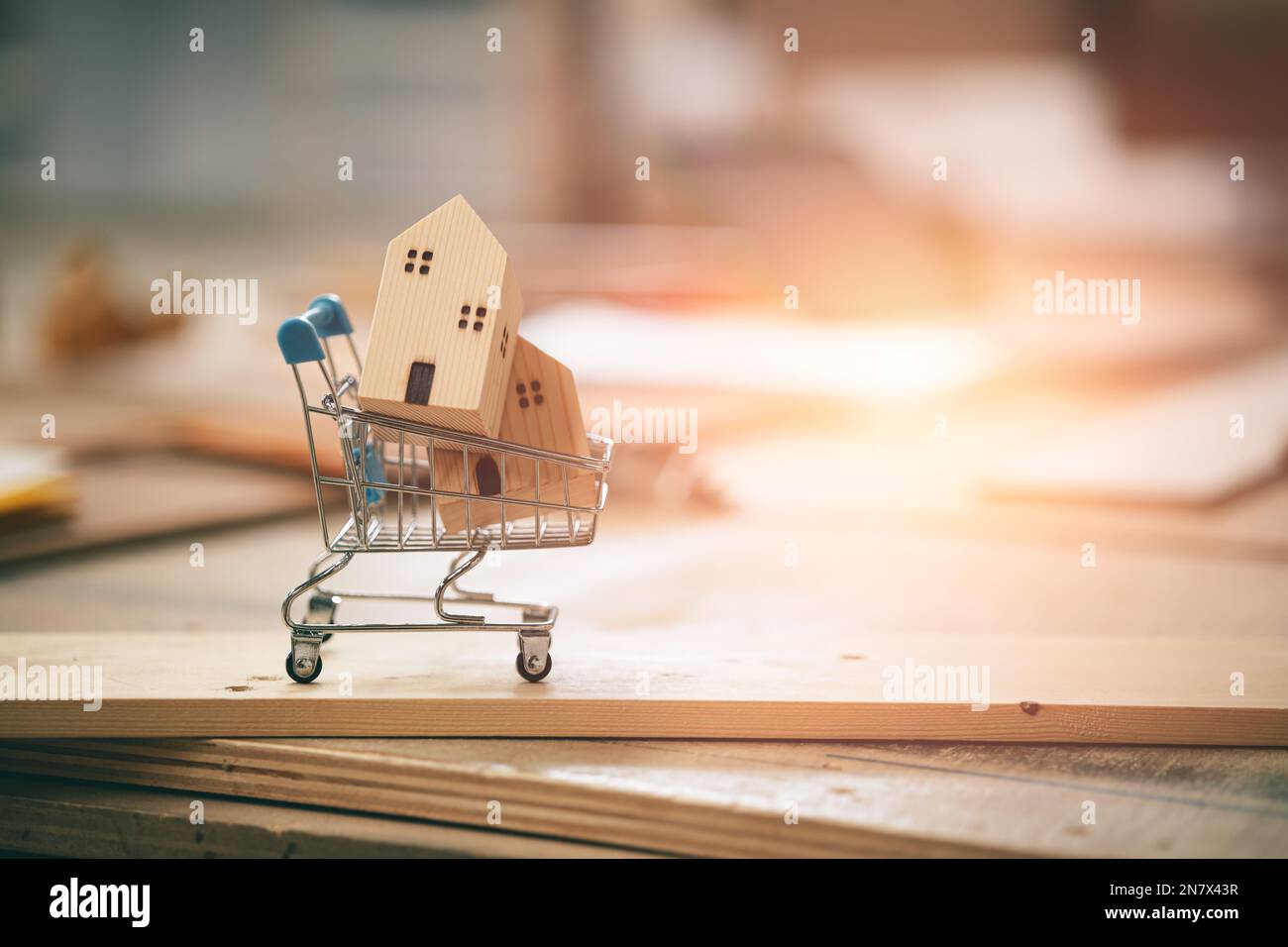 Kleines Holzhaus im Warenkorb zum Kauf eines neuen Hausbaums Holzhaus Konzept mit Kopierraum Stockfoto