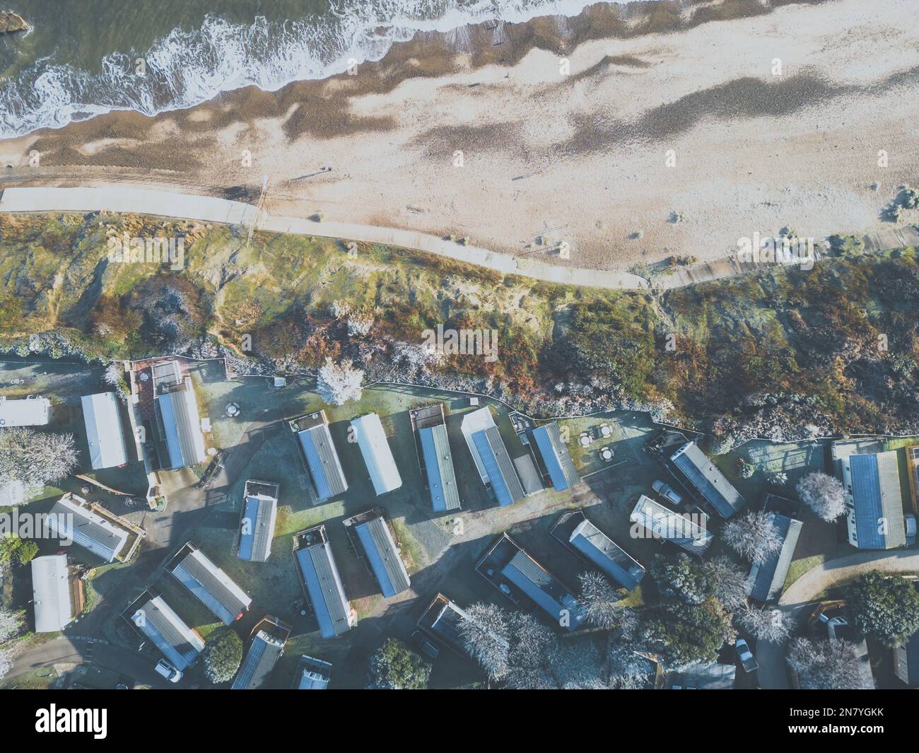 Drohnenblick auf Ferienhütten in der Nähe einer Küste im Winter. Frost ist auf den Dächern zu sehen. Stockfoto