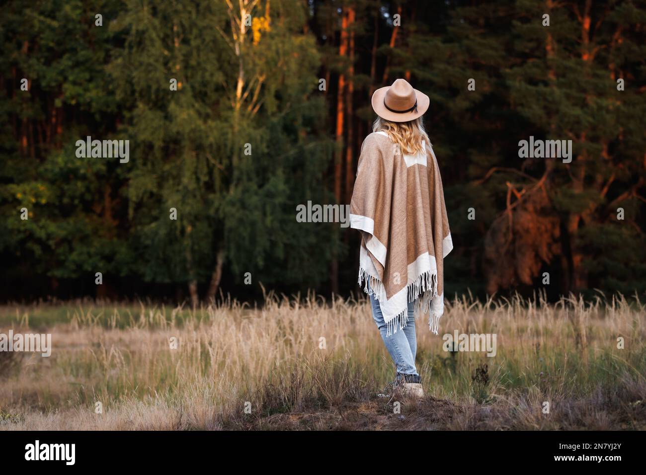 Frau mit Poncho und Cowboyhut im Freien. Boho-Mode-Style Stockfoto