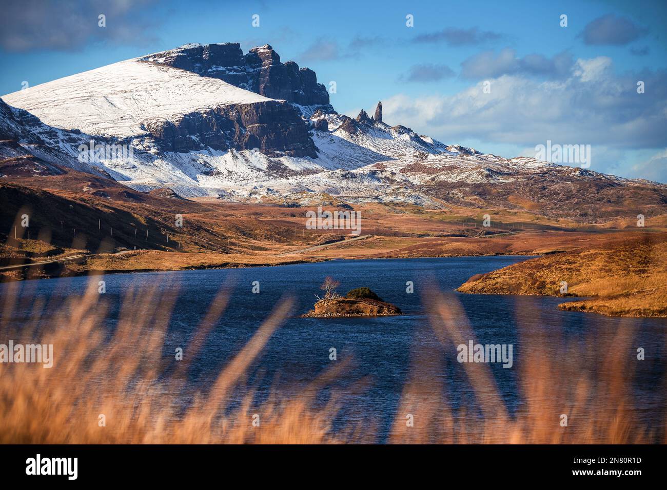 Isle of Skye, Schottland - das wunderschöne Loch Fada (See Fada) und die schneebedeckten Gipfel des Old man of Storr an einem sonnigen Frühlingsmorgen mit blauem Himmel und Wolken Stockfoto