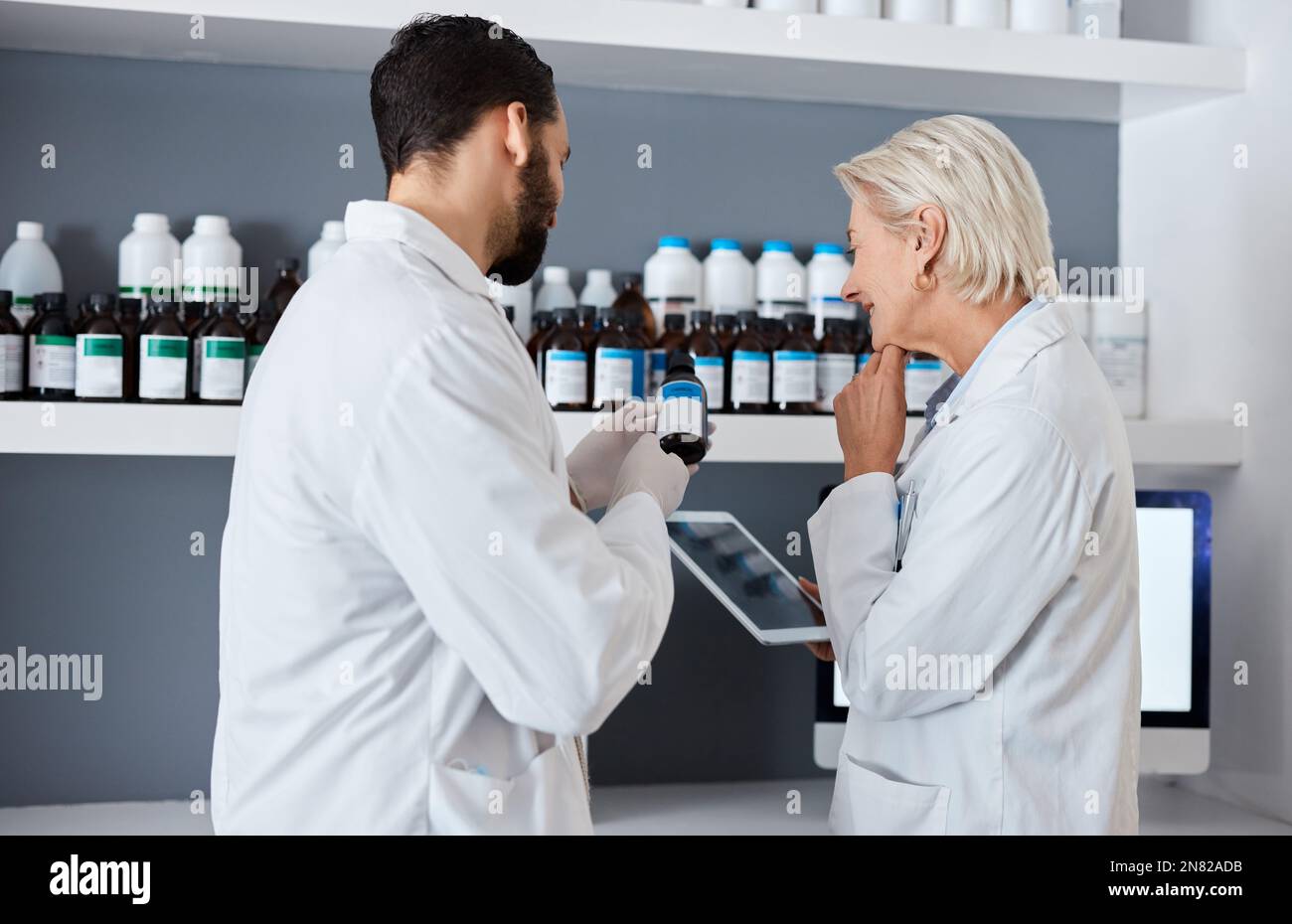 Wissenschaft, Medizin und Team mit Tablet im Labor für Impfstoff, medizinisches Gutachten und Forschung. Pharmazie, Gesundheitswesen und Wissenschaftler lesen Label von Stockfoto