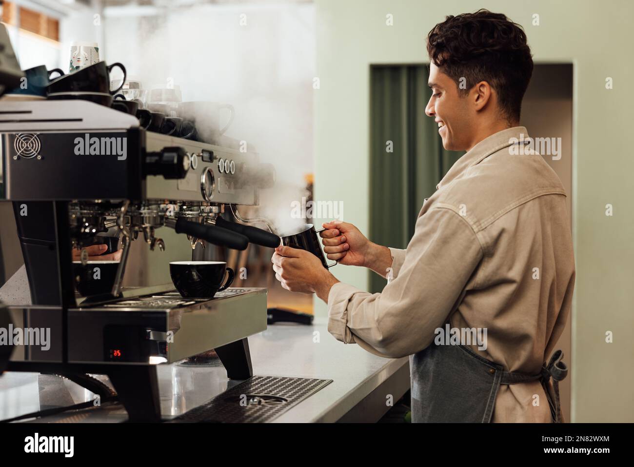Seitenansicht eines Baristas, der eine Kaffeemaschine verwendet. Der Besitzer des Cafés bereitet Kaffee zu. Stockfoto