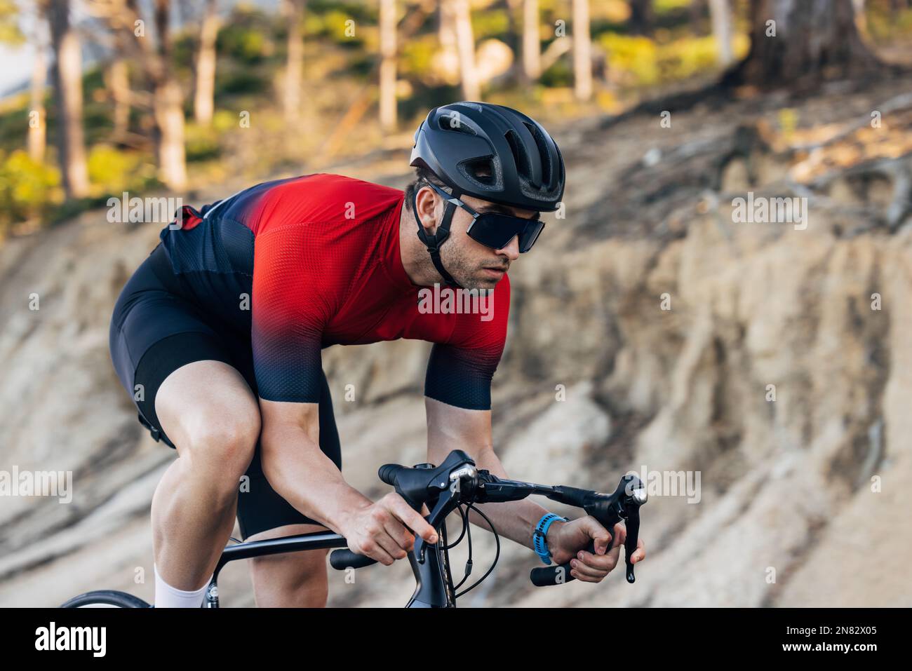 Professioneller männlicher Radfahrer, der draußen mit dem Fahrrad fährt. Radfahrer in Sportkleidung, der auf einem Road Bike trainiert. Stockfoto