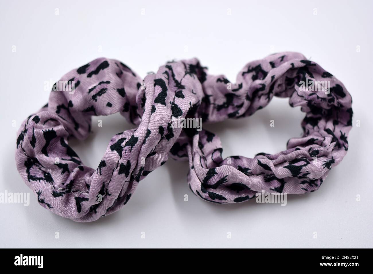 Auf weißem Hintergrund befindet sich ein Interessantes, elastisches Damenband aus Violett mit schwarzen Punkten aus Haargewebe. Stockfoto