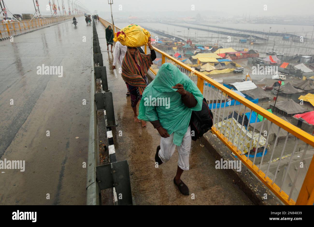 Hindu devotees walk in the rain at Sangam, the confluence of the Rivers ...