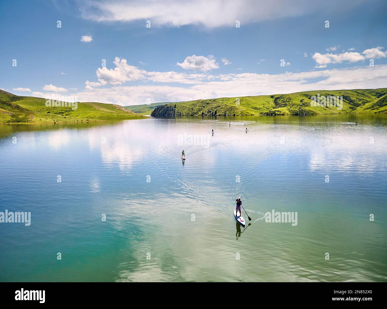 Top-down-Drohne Aufnahme einer Gruppe von Menschen in Stand-Up-Paddle-Boards SUP im Bergsee in der Nähe der grünen Hügel in Kasachstan Zentralasien Stockfoto
