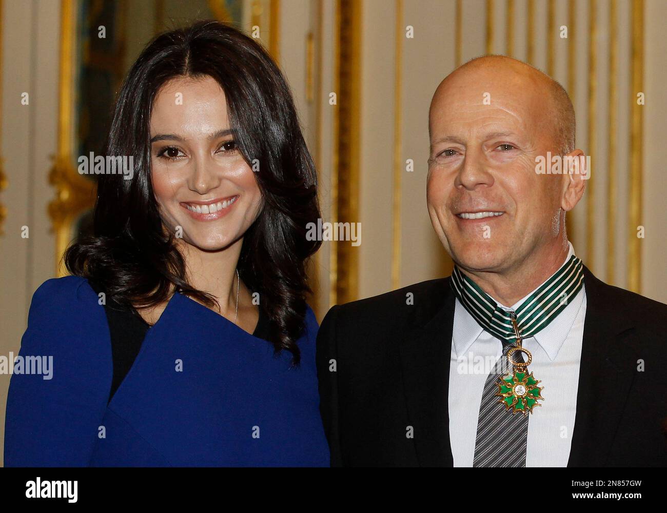American movie star Bruce Willis, poses for the press with his wife model Emma Heming, left, after being awarded with the medal of Commander of Arts and Letters by French culture minister Aurelie Filippetti, in Paris, Monday Feb. 11, 2013.(AP Photo/Remy de la Mauviniere) Stockfoto