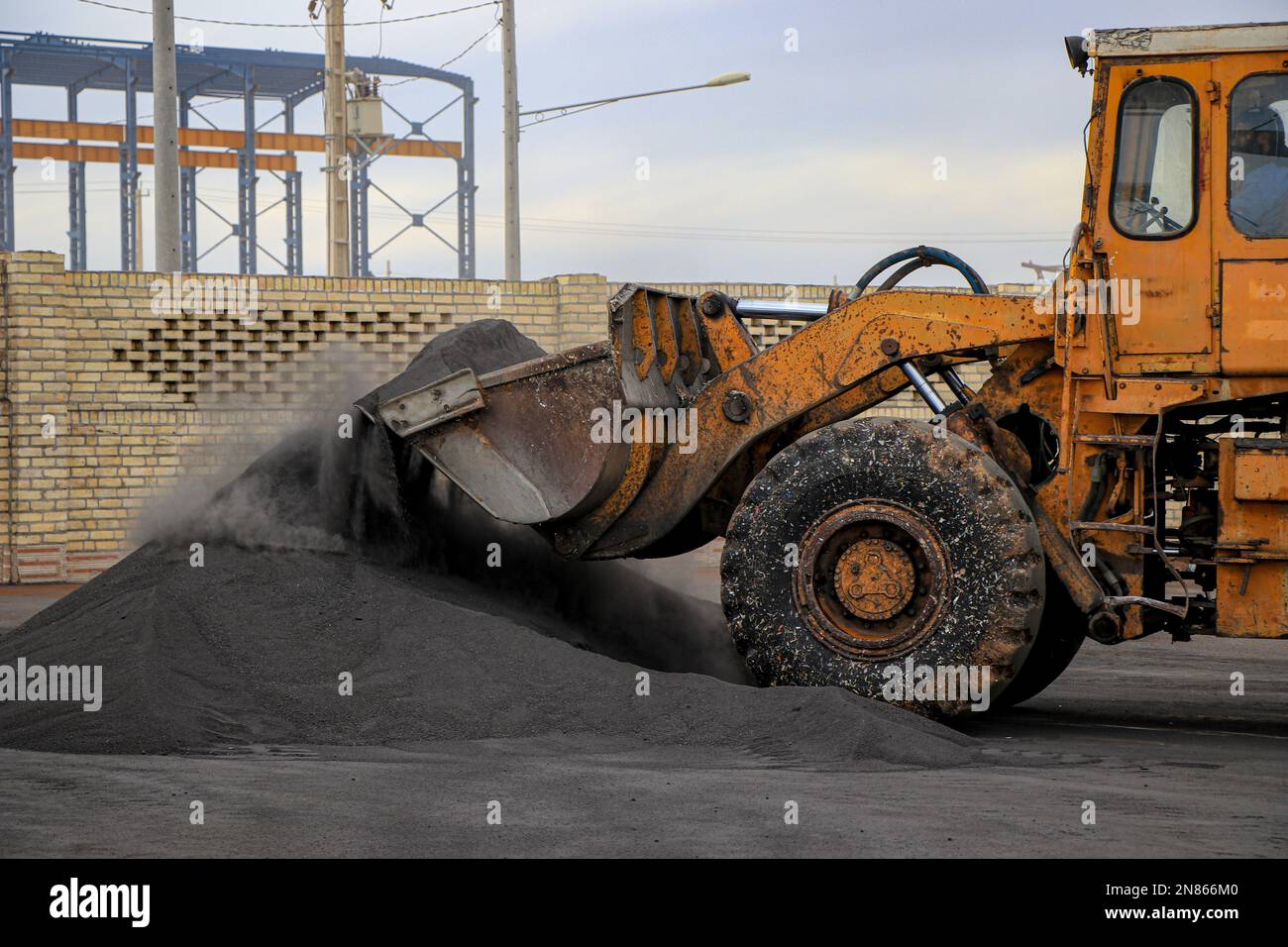 Ein Hydraulikbagger, der den Boden gräbt und schwarzen Staub für Bauzwecke auflädt. Stockfoto