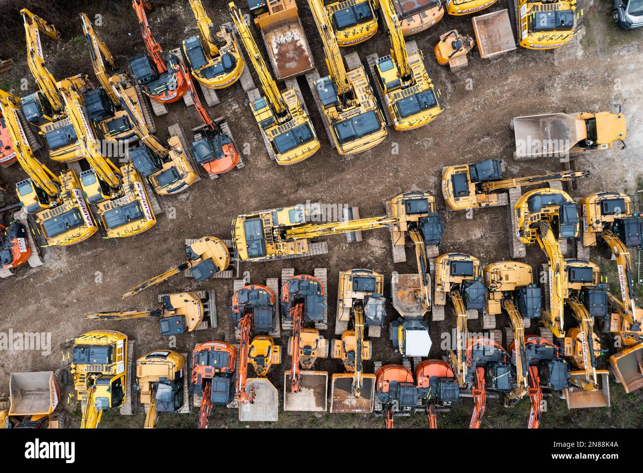 Luftaufnahme direkt über einem Vermietungsgelände für Industriemaschinen mit Grabern und Bulldozern, die zusammen in einem industriellen Hintergrund geparkt sind Stockfoto