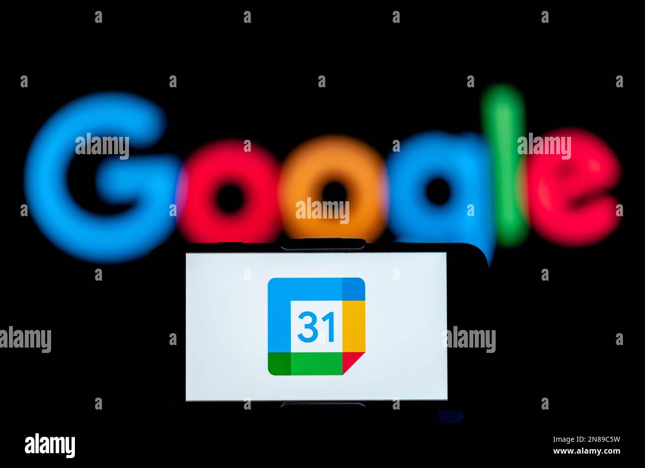 In dieser Fotoabbildung wird das Logo des google-Kalenders auf dem Bildschirm eines Mobiltelefons mit einem google-Logo im Hintergrund angezeigt. Stockfoto