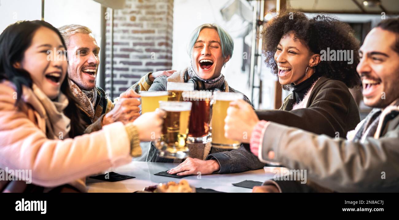 Fröhliche Freunde trinken und toasten Bier im Brauereirestaurant - das Speise- und Getränkekonzept mit jungen, vielfältigen Menschen, die Spaß miteinander haben Stockfoto