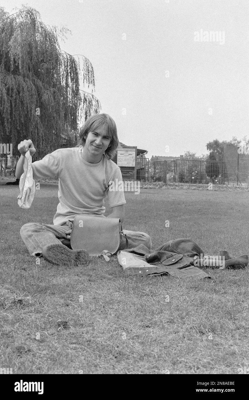 Grinsender junger Mann, der seine Freundinnen hochhält, saubere Unterwäsche, die er aus ihrer unbewachten Handtasche im öffentlichen Park 1980er Rugby uk genommen hat Stockfoto
