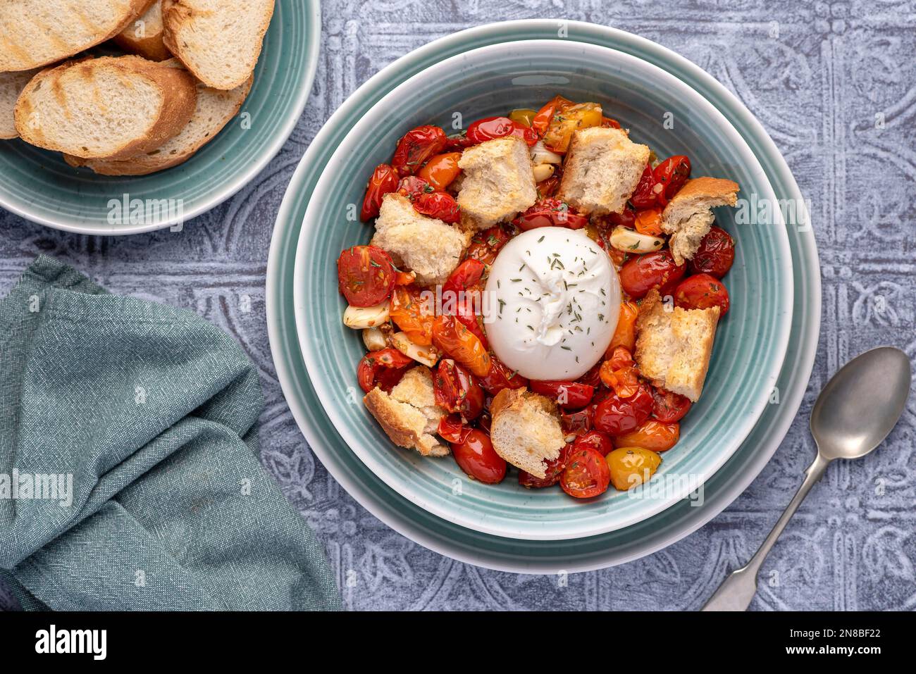 Lebensmittelfotografie von gebackenen Tomaten, Käse, Burrata, Mozzarella, Knoblauch, Crouton, Thymian, Toast Stockfoto