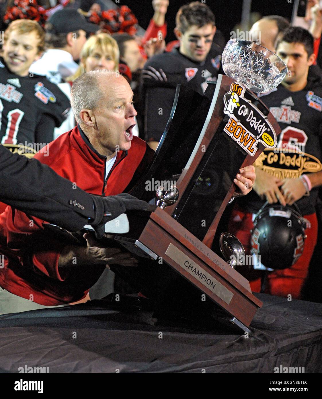 Arkansas State interim head coach John Thompson struggles to lift the champions trophy following the Red Wolves' 17-13 victory over Kent State in the 2013 GoDaddy.com Bowl NCAA college football game in Mobile, Ala., Sunday, Jan. 6, 2013. (AP Photo/G.M. Andrews) Stockfoto