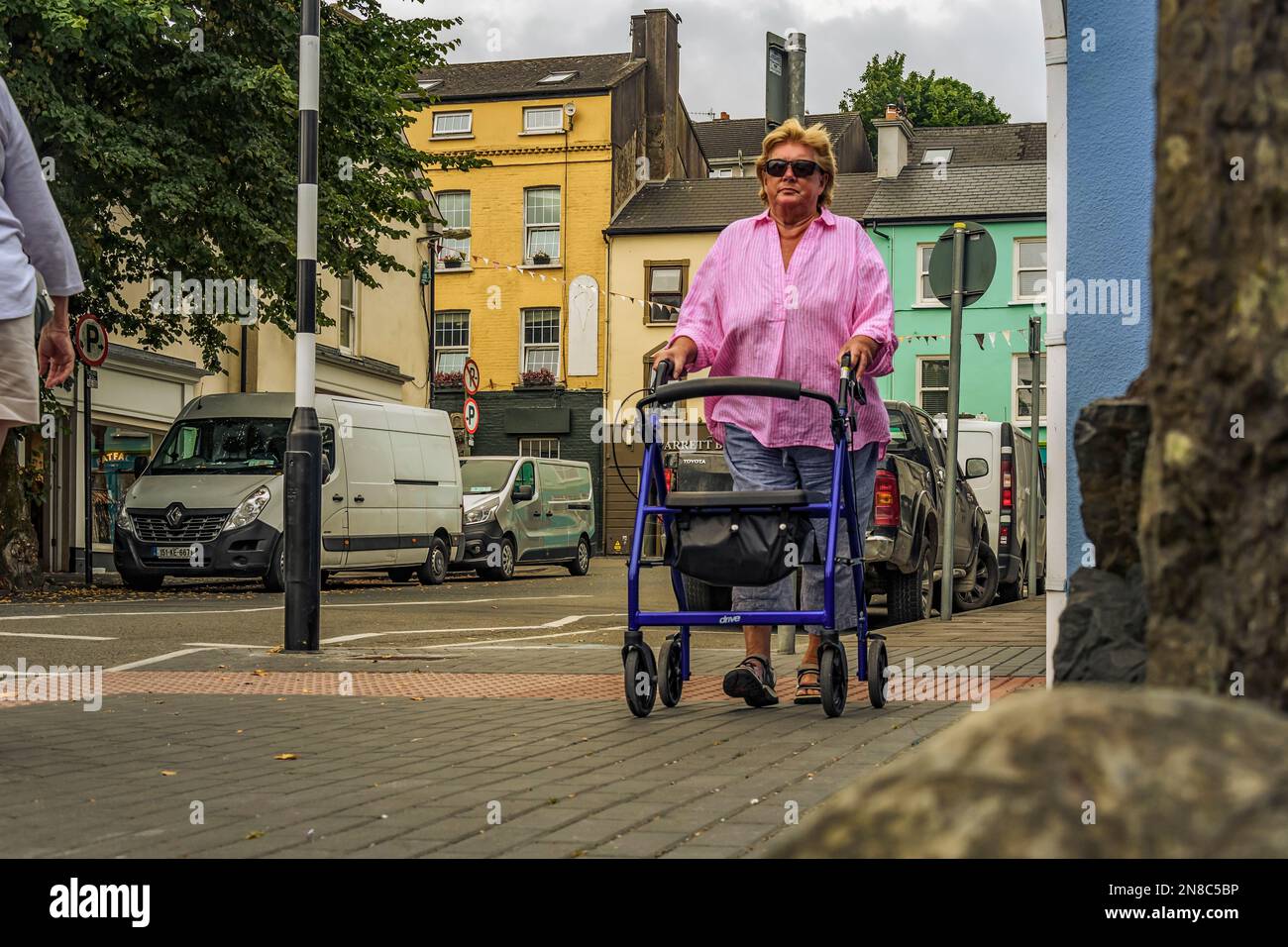 Dame mit besonderen Bedürfnissen mit Rollator im Stadtzentrum von Kinsale, CO Cork, Irland. Stockfoto