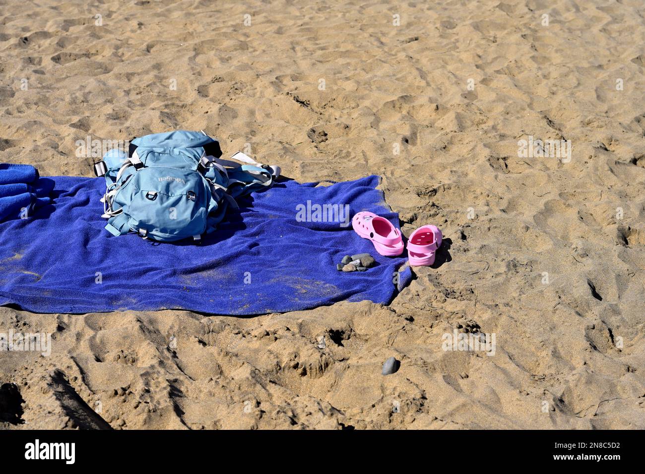 Leeres Strandtuch, Tasche und Schuhe am Sandstrand Stockfoto